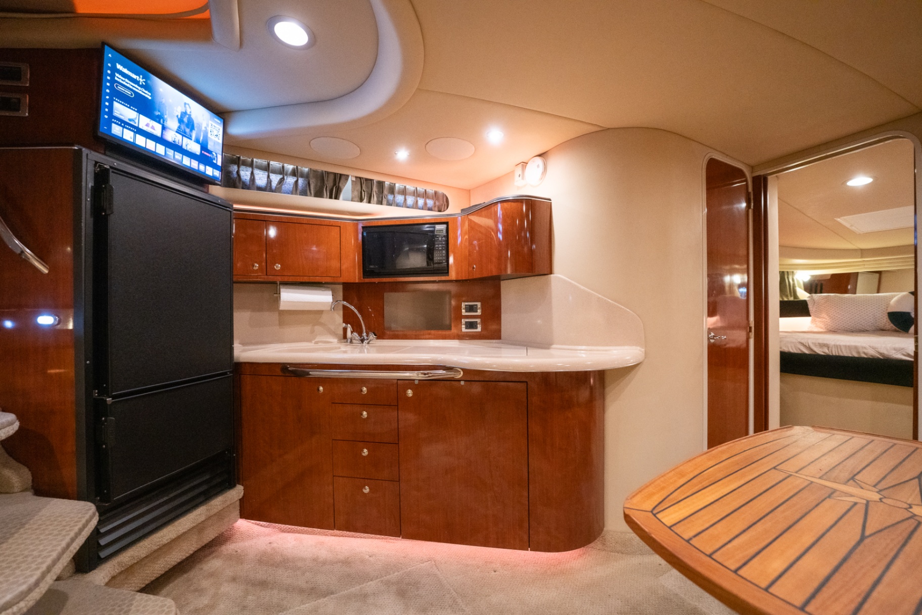 Below-deck galley with refrigerator, microwave, and glossy wood cabinetry