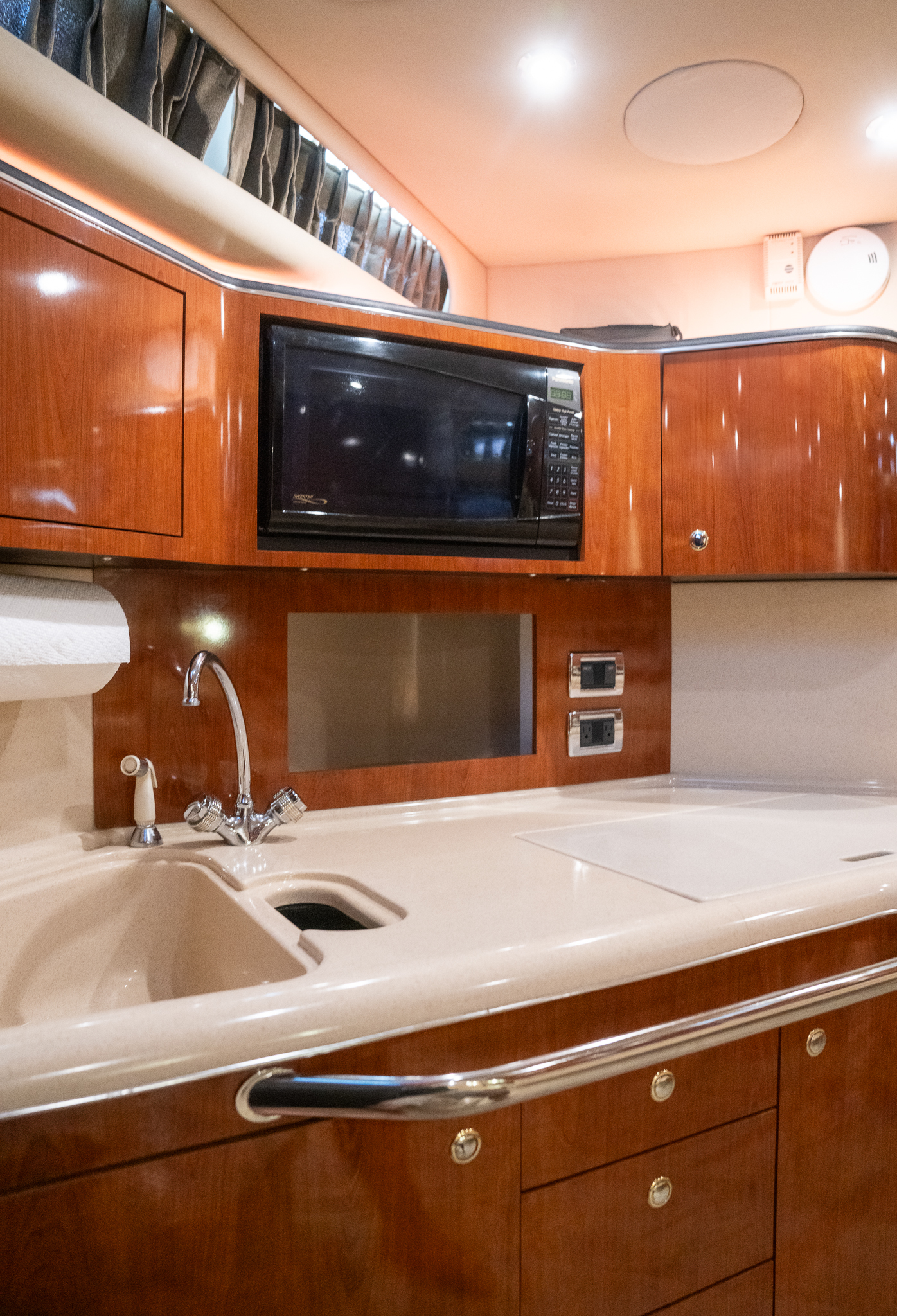 Galley with refrigerator, sink, microwave, and glossy wood cabinetry