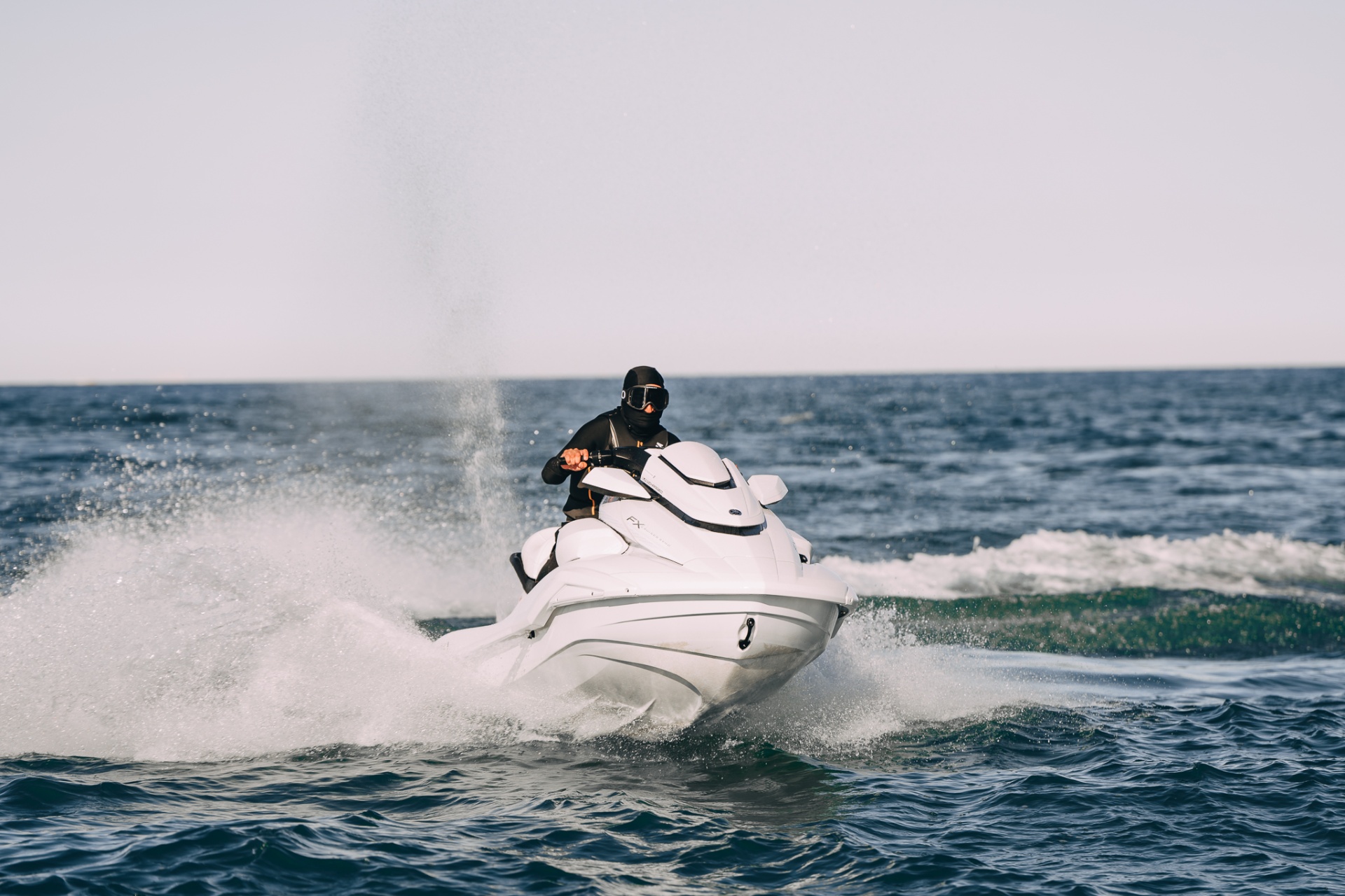 White FX Cruiser launching over open-water chop